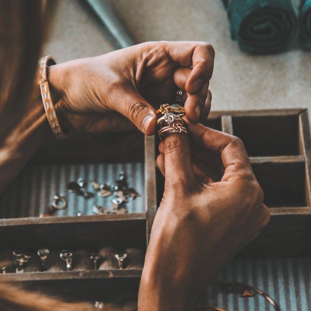 Woman's hand holding three handmade metal rings in three different types of metal.